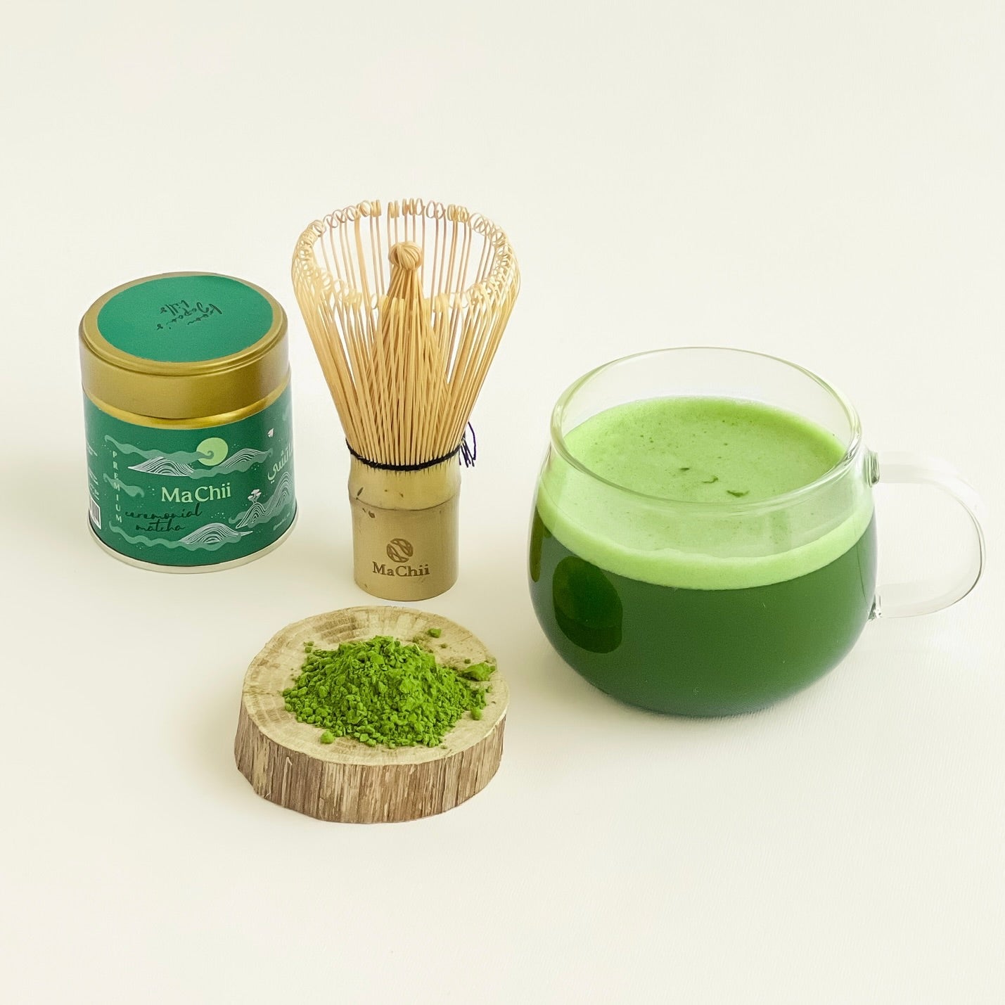 ceremonial matcha premium with a matcha whisk and a cup of traditional matcha. powder on the side of the cup. machii tea logo