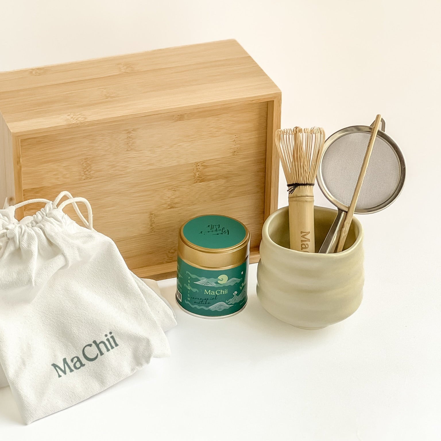 Tea-making set with wooden box, green tea canister, and ceramic container on a white background